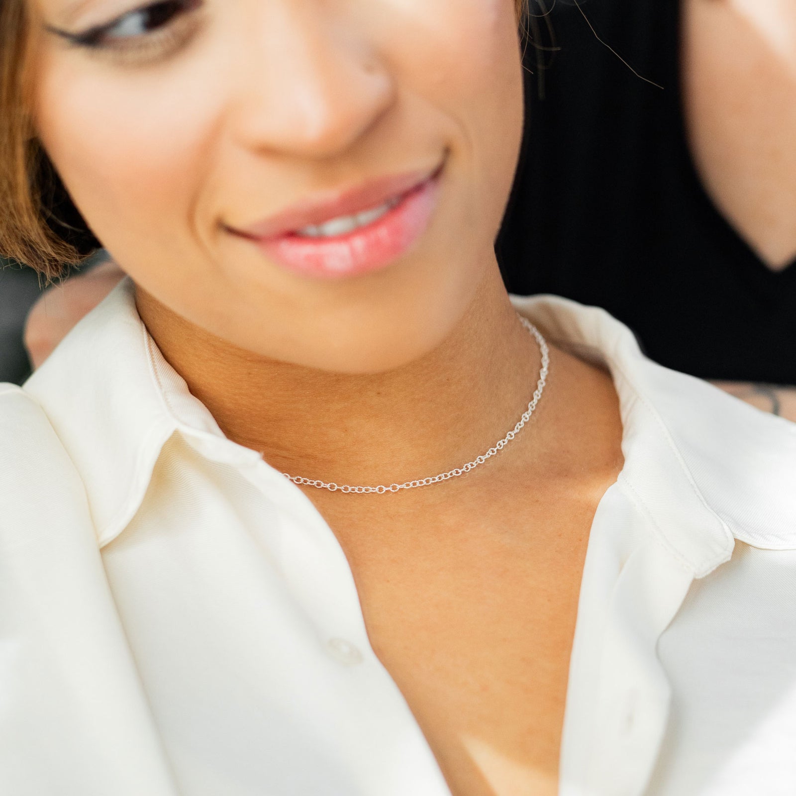 Close-up of a woman wearing a silver necklace with a blurred background