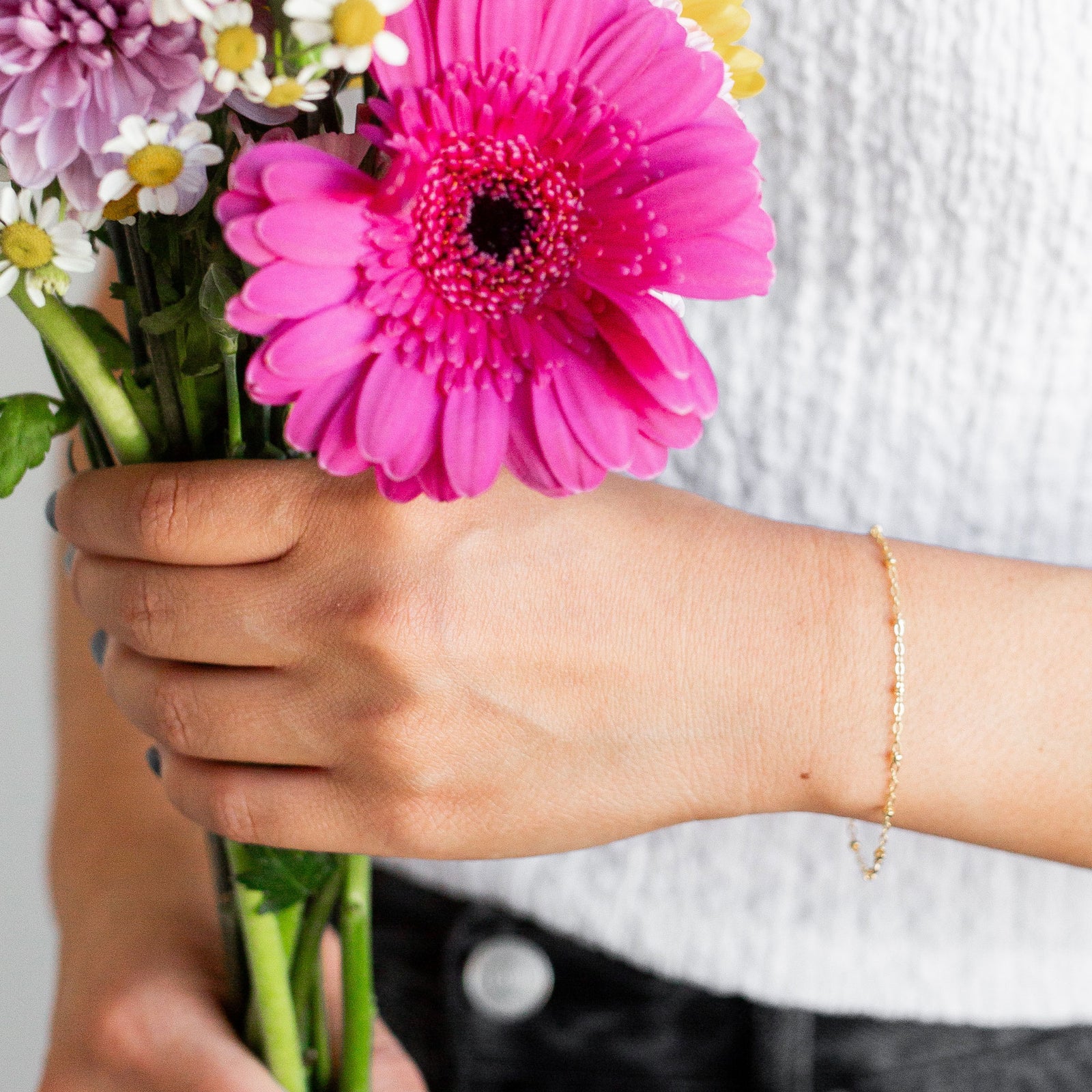 Hand holding a bouquet of flowers with a pink flower in focus