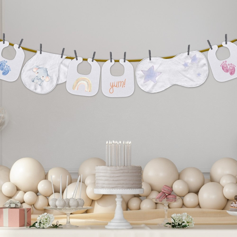 Engraved baby bibs hanging above a cake made to celebrate the mother to be.