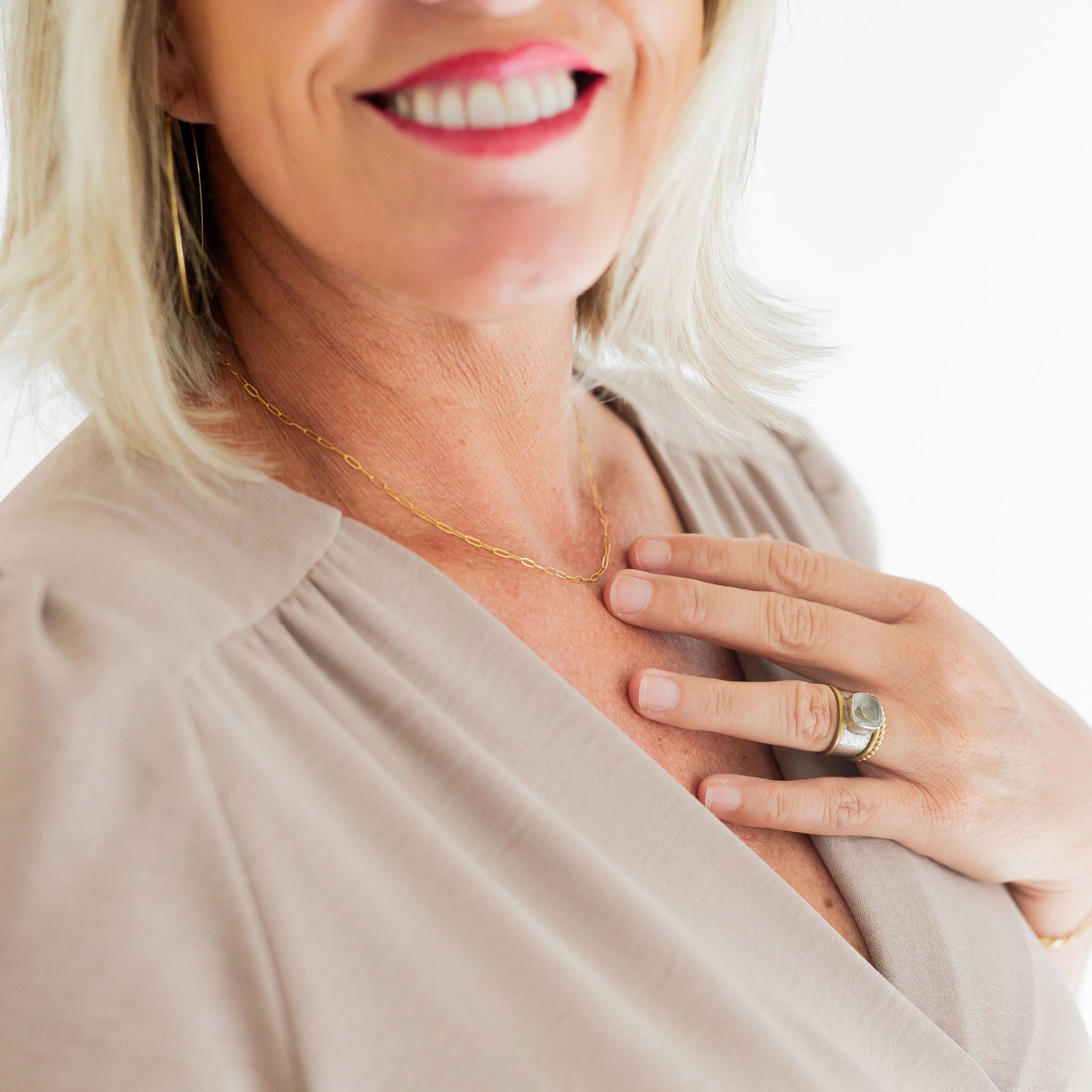 Woman wearing a gold necklace and ring on a white background