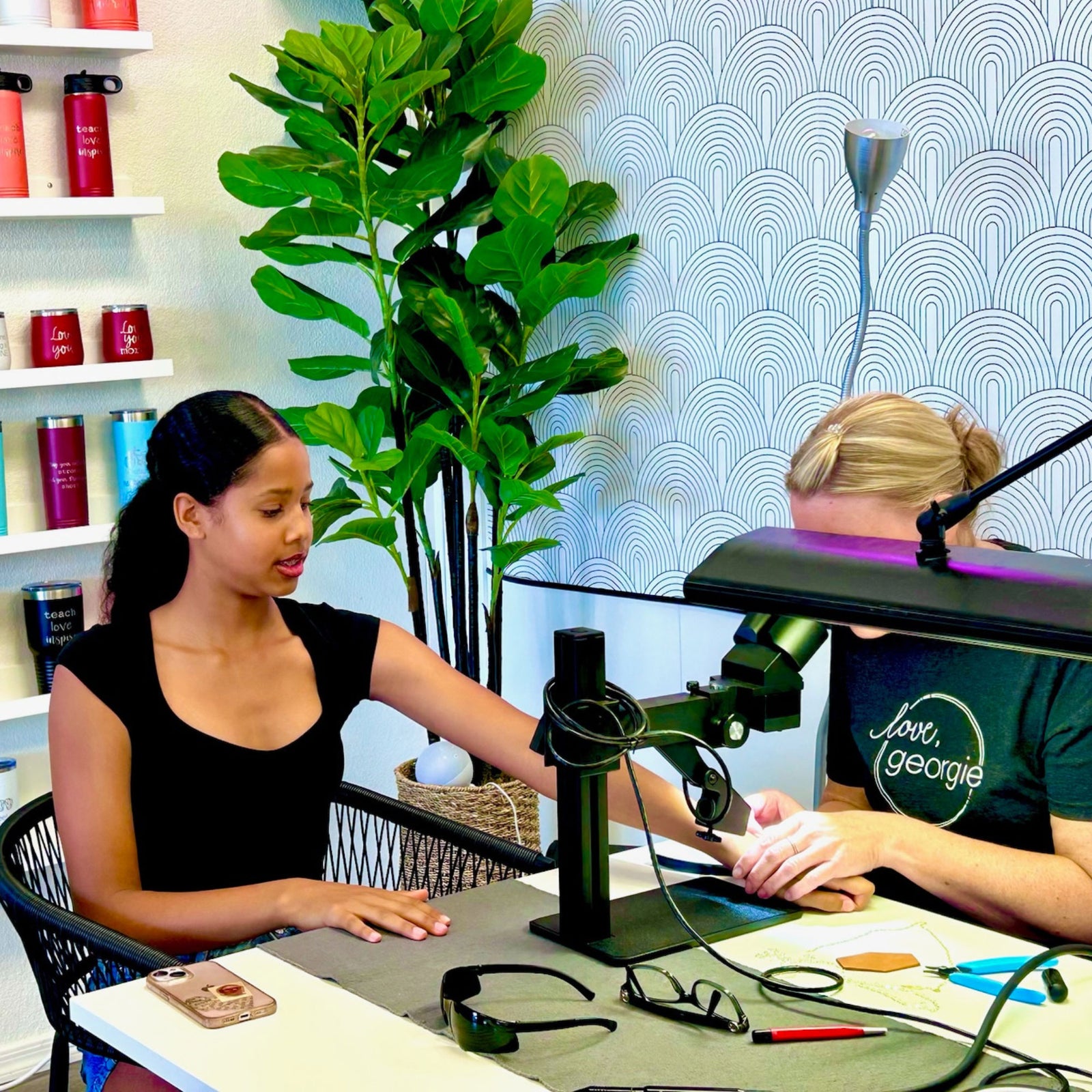 Woman getting permanent jewelry put on at Love, Georgie