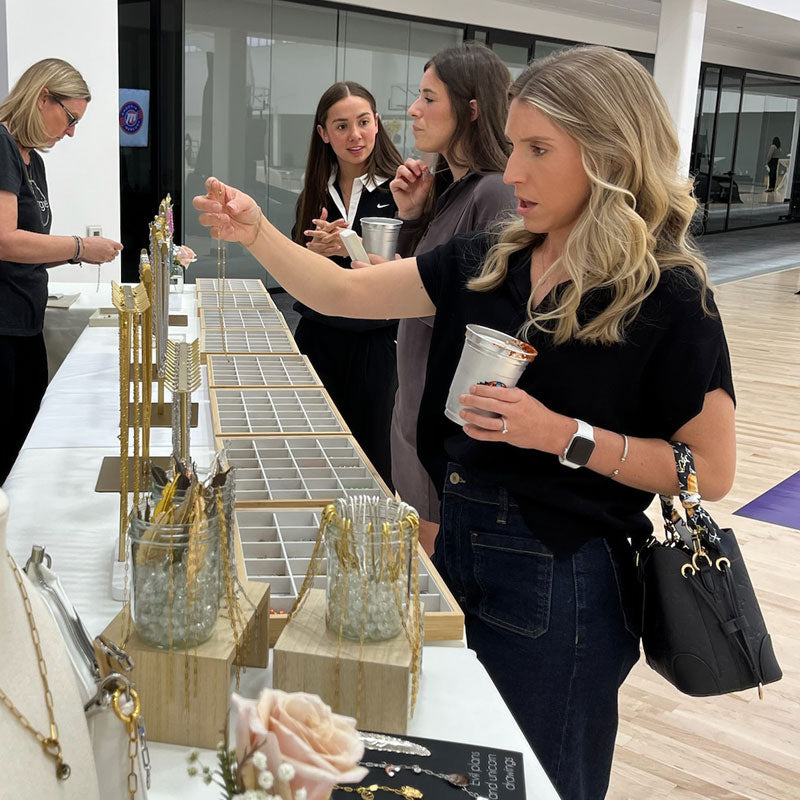 Woman checking out a piece of jewelry at a charm bar table.