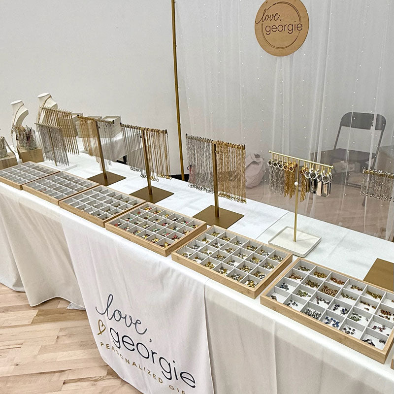 Charm bar display setup on a table with 'Love, Georgie' branding.