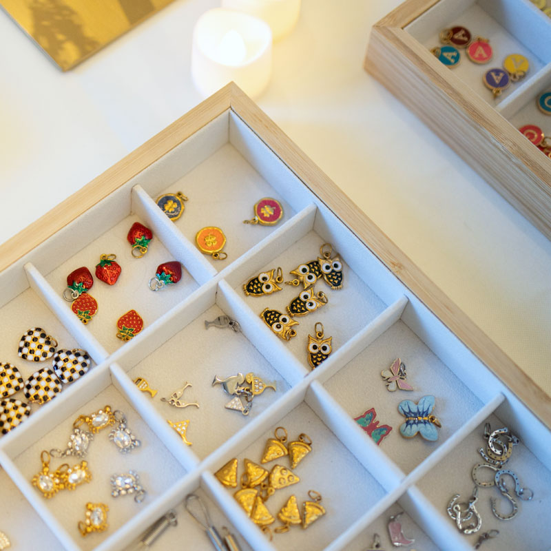 Collection of small jewelry charms in a wooden box with compartments.