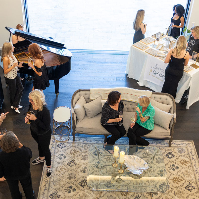 People socializing in a room with a piano, couch, and a charm bar table.