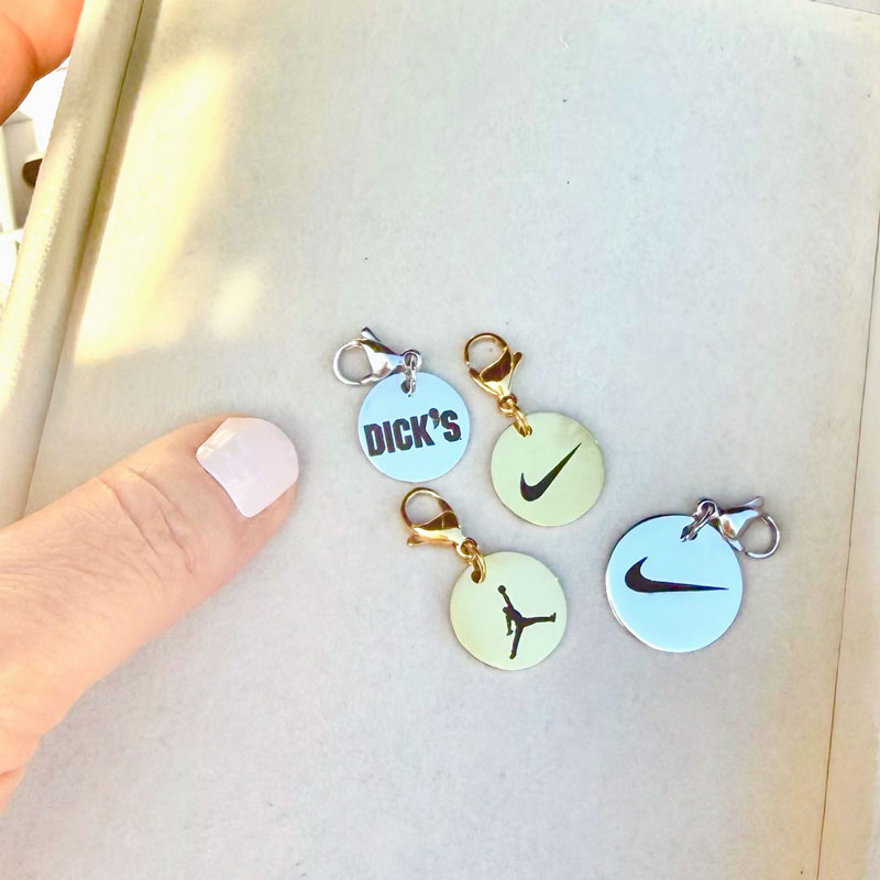 Four keychain charms with brand logos against a light background.