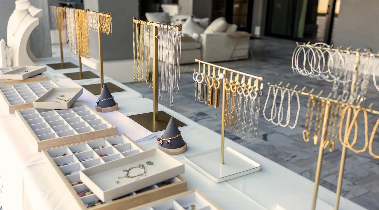 Jewelry charm display with gold & silver accessories on stands and trays in a store setting.