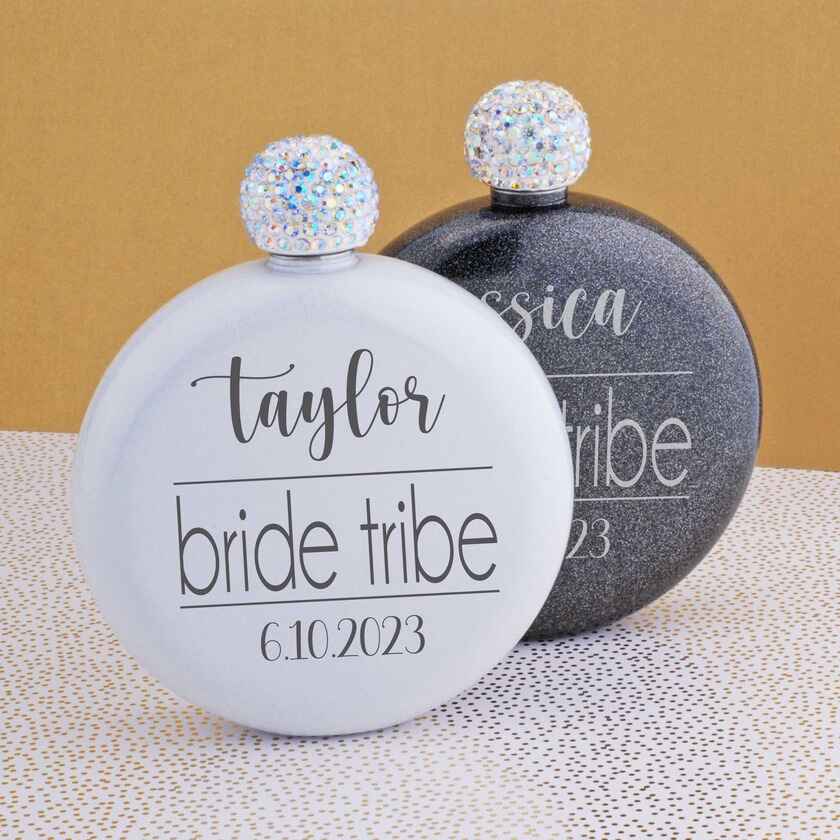 a pair of round stainless steel flasks with jeweled tops. they are engraved with a woman's name, the phrase "bride tribe", and a wedding date