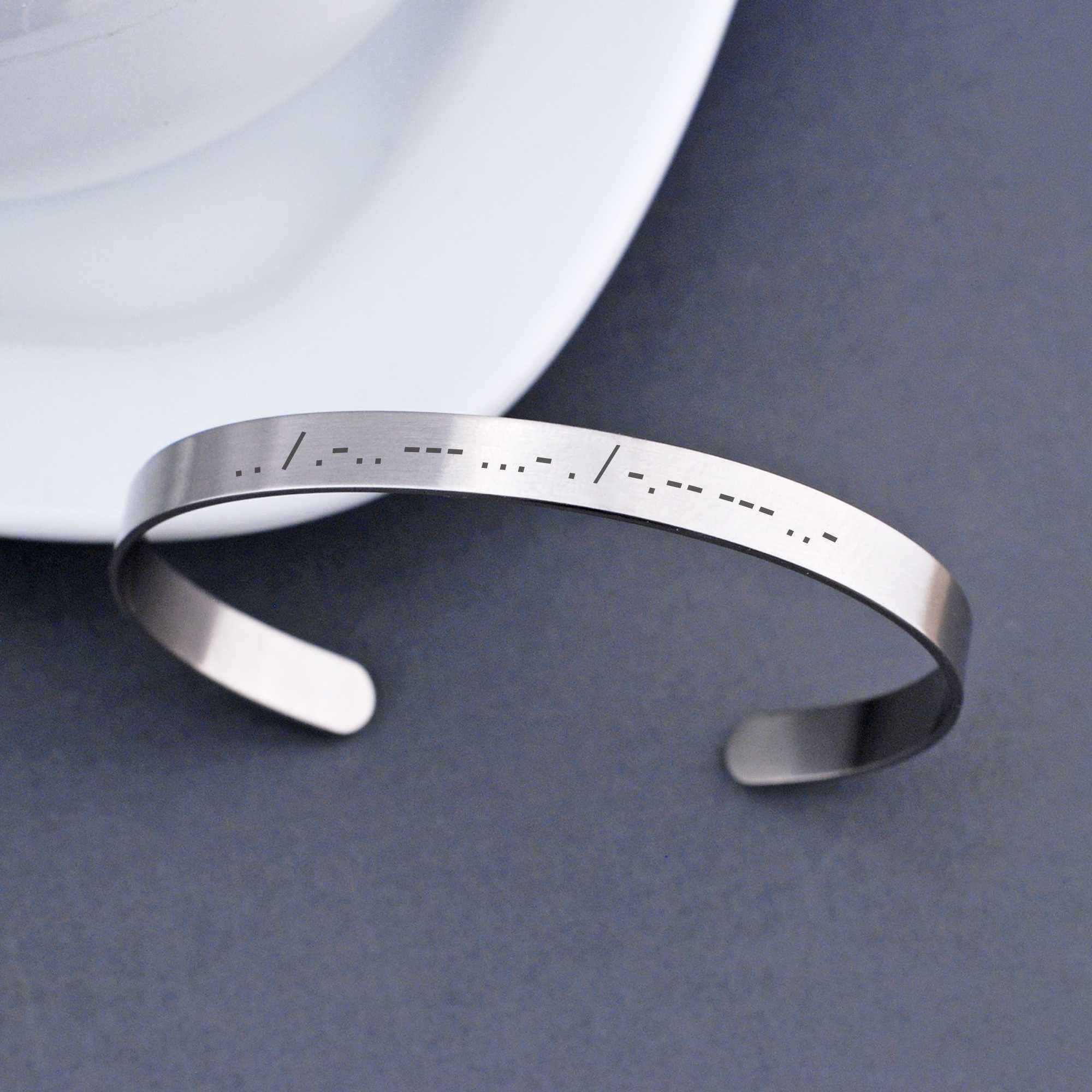 Wear a secret message in plain sight with our Morse Code Cuff Bracelet. It is engraved with the morse code translation of up to 20 characters. The adjustable stainless steel bracelet can also hold a second morse code message of 20 characters or a message of up to 50 standard characters on the inside surface. Made by Love, Georgie.